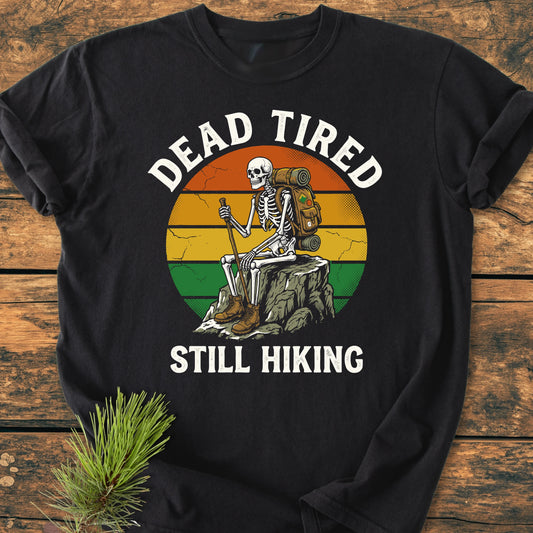 Dead Tired - Vintage Wash Tee: Black long-sleeve shirt featuring a retro-style circle with a cartoon skeleton hiking, surrounded by DEAD TIRED and STILL HIKING text, styled with a pine branch.