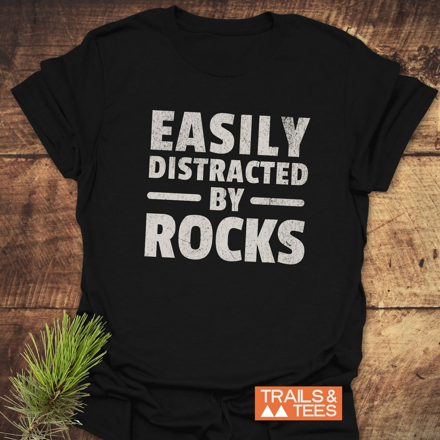 Easily Distracted By Rocks T-Shirt featuring white text on black, crafted from lightweight cotton for comfort, ideal for outdoor enthusiasts seeking adventure-ready apparel.