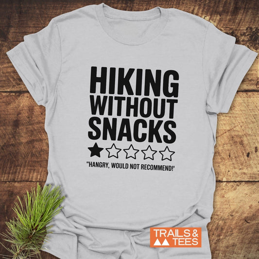 Close-up of the Hiking Without Snacks T-Shirt featuring bold text, shown alongside a houseplant for a natural, active lifestyle vibe.