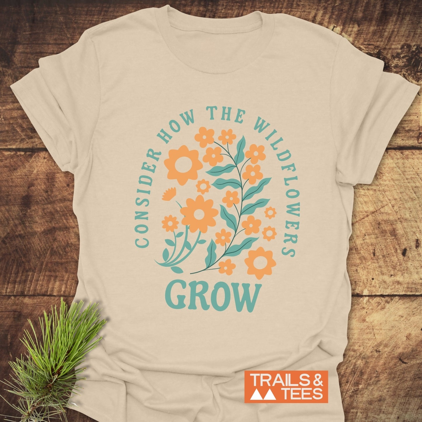 Wildflowers Luke 12:27 T-Shirt featuring a graphic design of blue and orange flowers, crafted from soft cotton for comfort and durability.