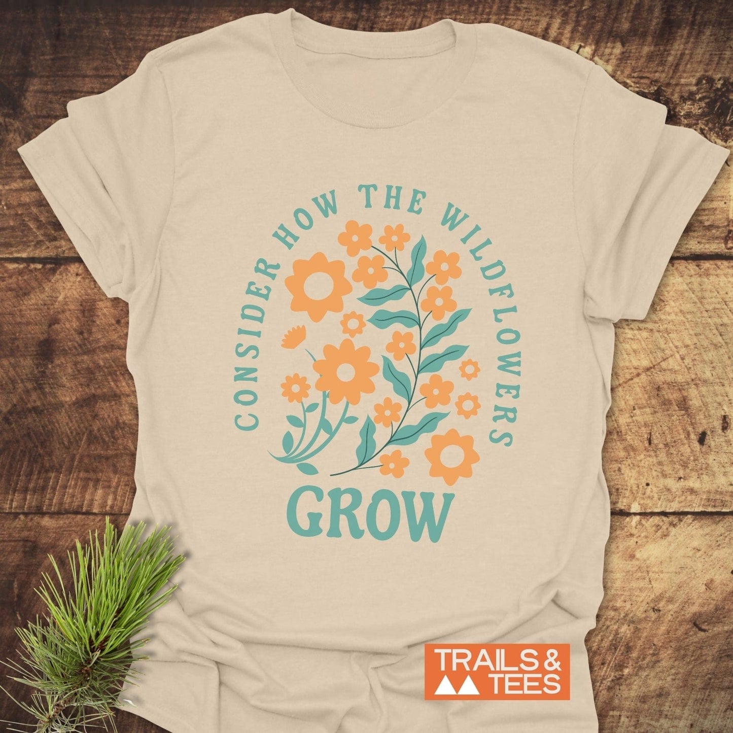 Wildflowers Luke 12:27 T-Shirt featuring a graphic design of blue and orange flowers, crafted from soft cotton for comfort and durability.