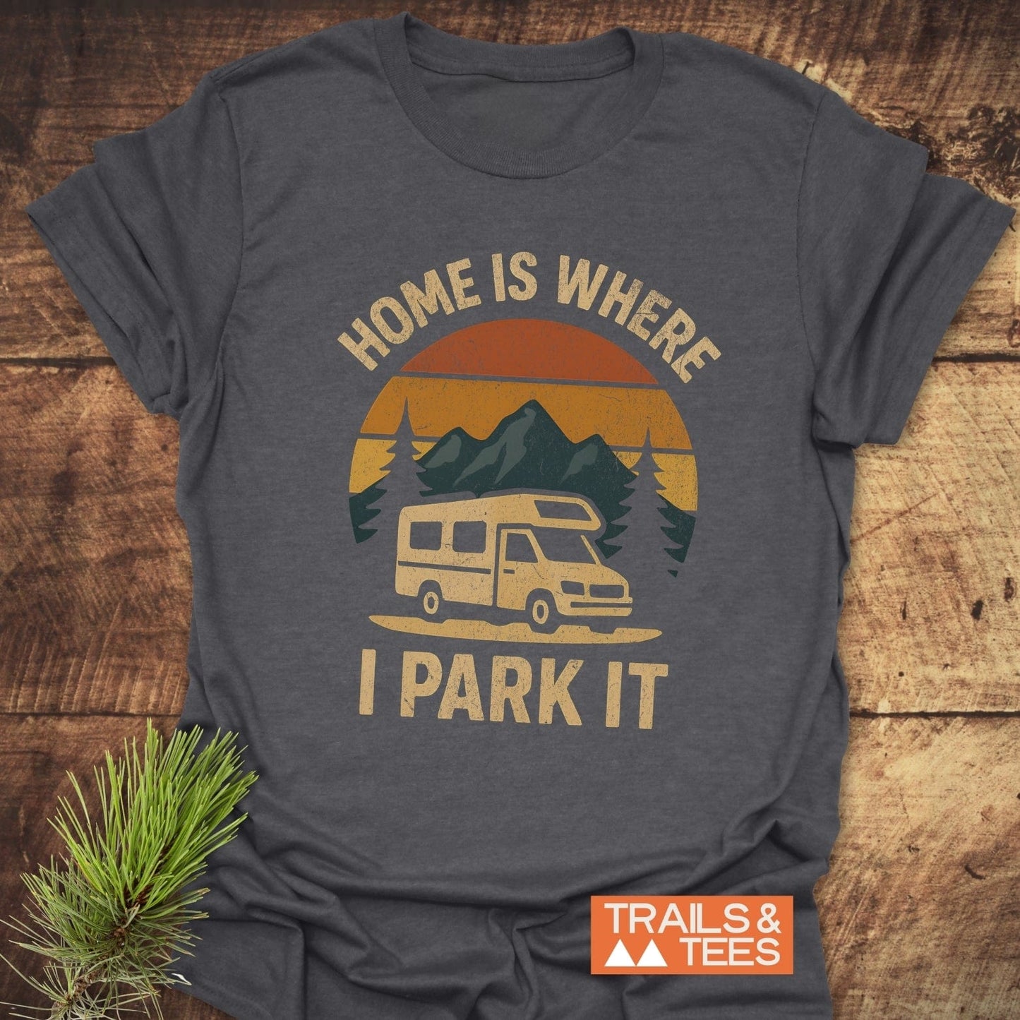 Home Is Where I Park It T-Shirt featuring a camper van, mountains, and pine branch design, crafted from soft cotton for daily outdoor adventures.