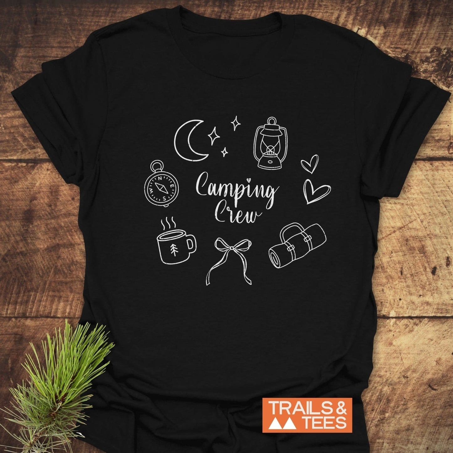 Camping Crew T-Shirt featuring a white compass line drawing and bold text design on a black shirt, epitomizing adventurous spirit and outdoor style.