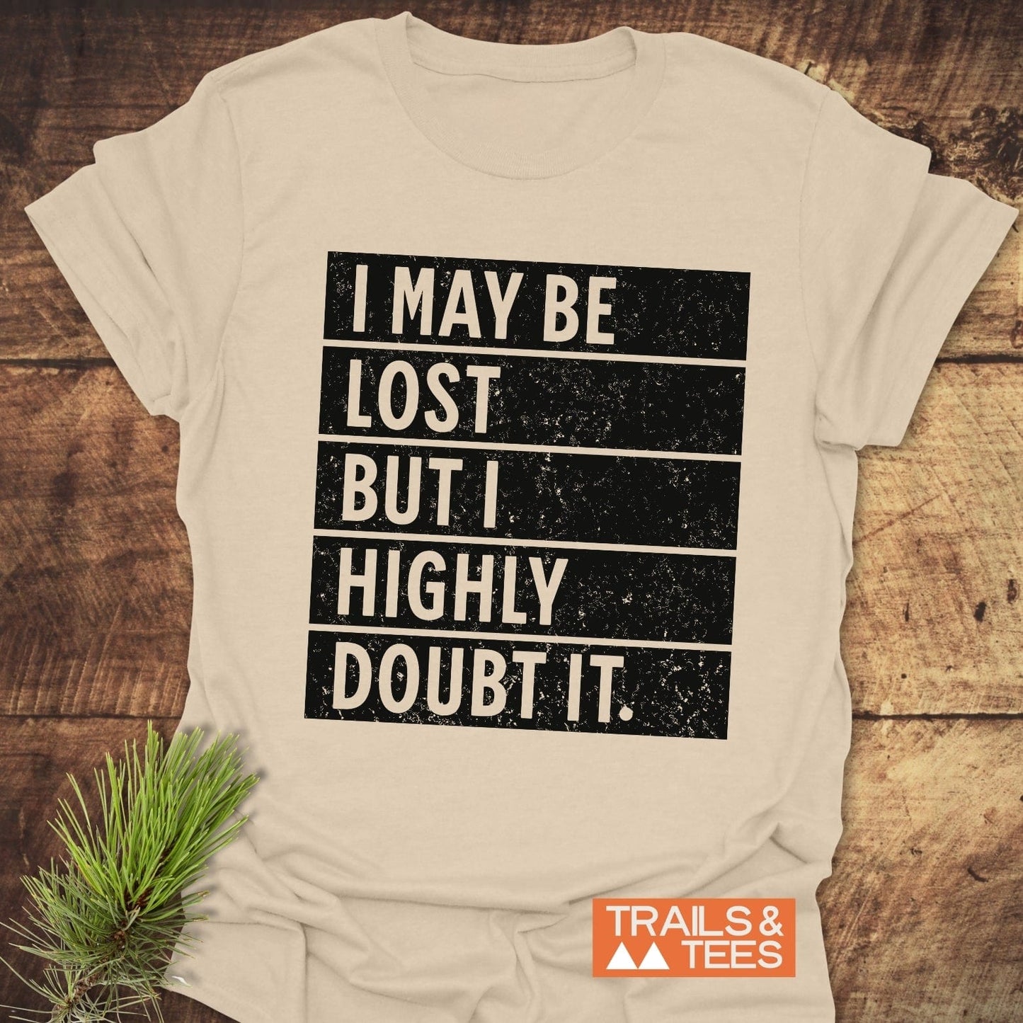 White t-shirt displaying I May Be Lost But I Highly Doubt It in black text, designed for active wear, featured alongside a houseplant.