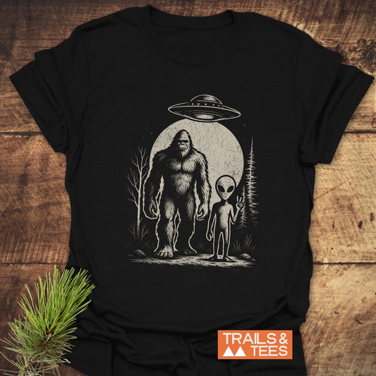 Bigfoot And Alien T-Shirt featuring a drawing of an alien and UFO, crafted from soft ring-spun cotton for comfort and adventure-ready durability.