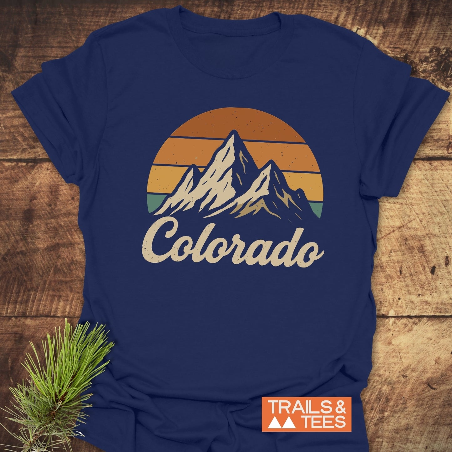 Colorado Sunset T-Shirt featuring mountain and pine branch graphics, designed for active wear, with visible logo details on a blue shirt.