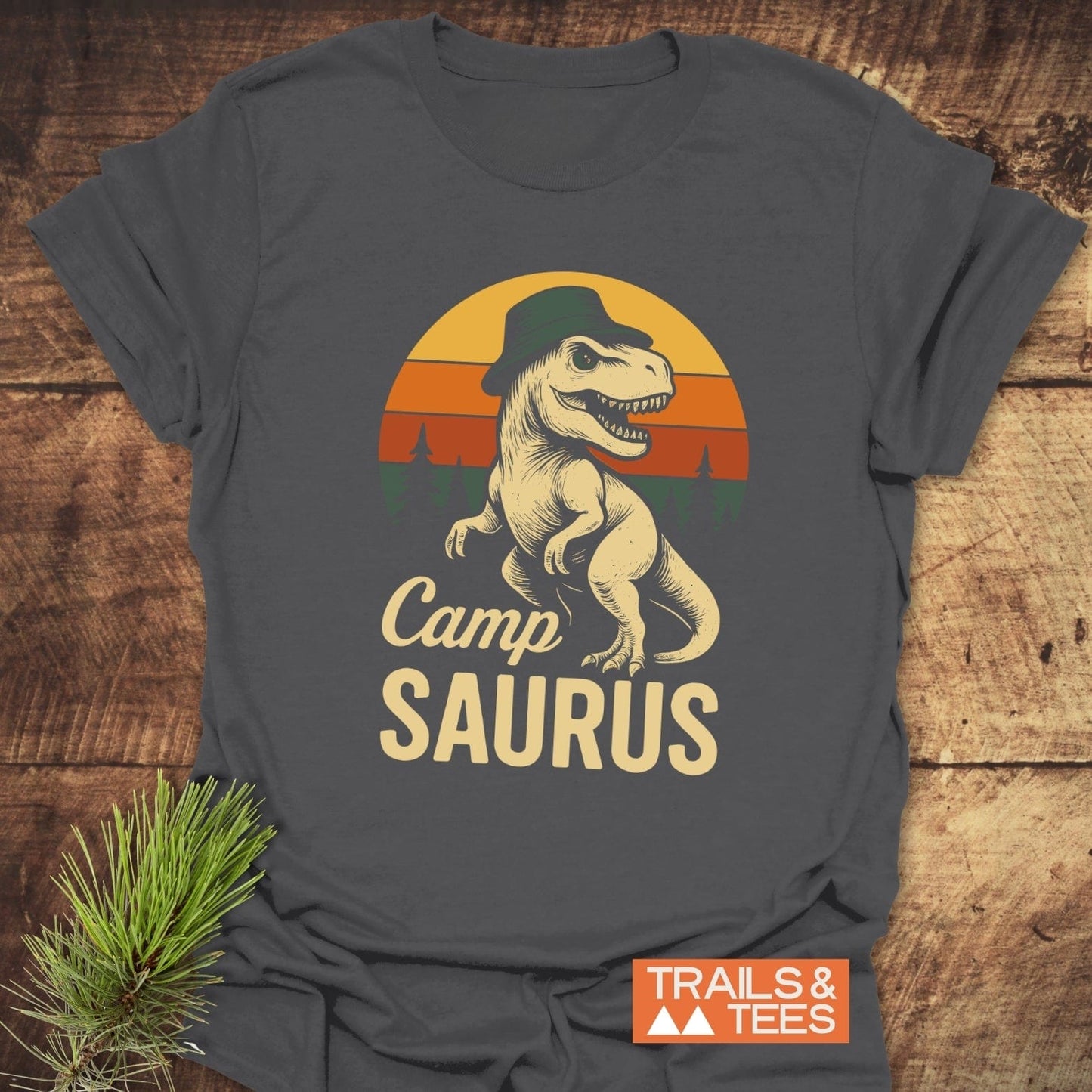 Cartoon dinosaur with a hat on CampSaurus T-Shirt, perfect for outdoor adventures. Made from soft ring-spun cotton with durable, non-fading DTF prints.