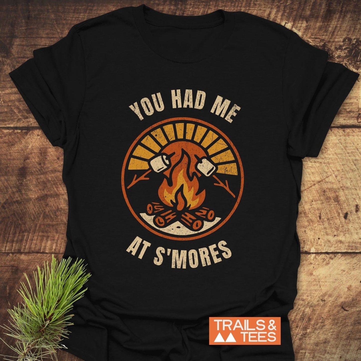 You Had Me At S'mores T-Shirt featuring a black design with white text and a drawing of a fire and marshmallows, crafted for outdoor comfort.
