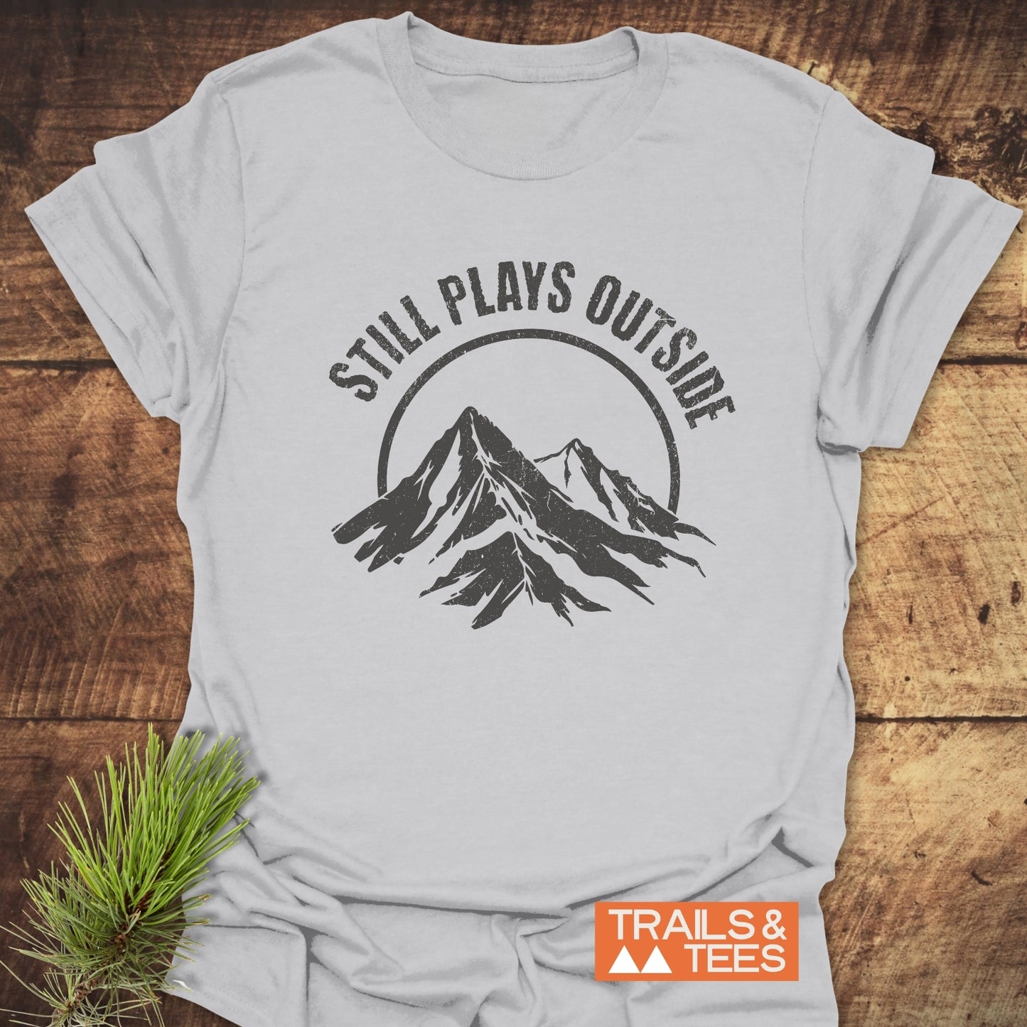 Still Plays Outside T-Shirt featuring a mountain graphic, crafted from soft ring-spun cotton, pre-shrunk for fit, and designed for outdoor enthusiasts.