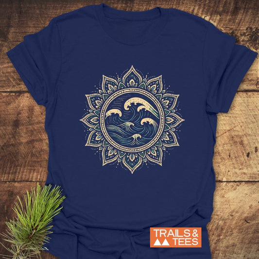 Ocean Mandala T-Shirt featuring a circular wave graphic with a lotus mandala, laid on wood. Includes “TRAILS & TEES” logo, emphasizing comfort and durability.
