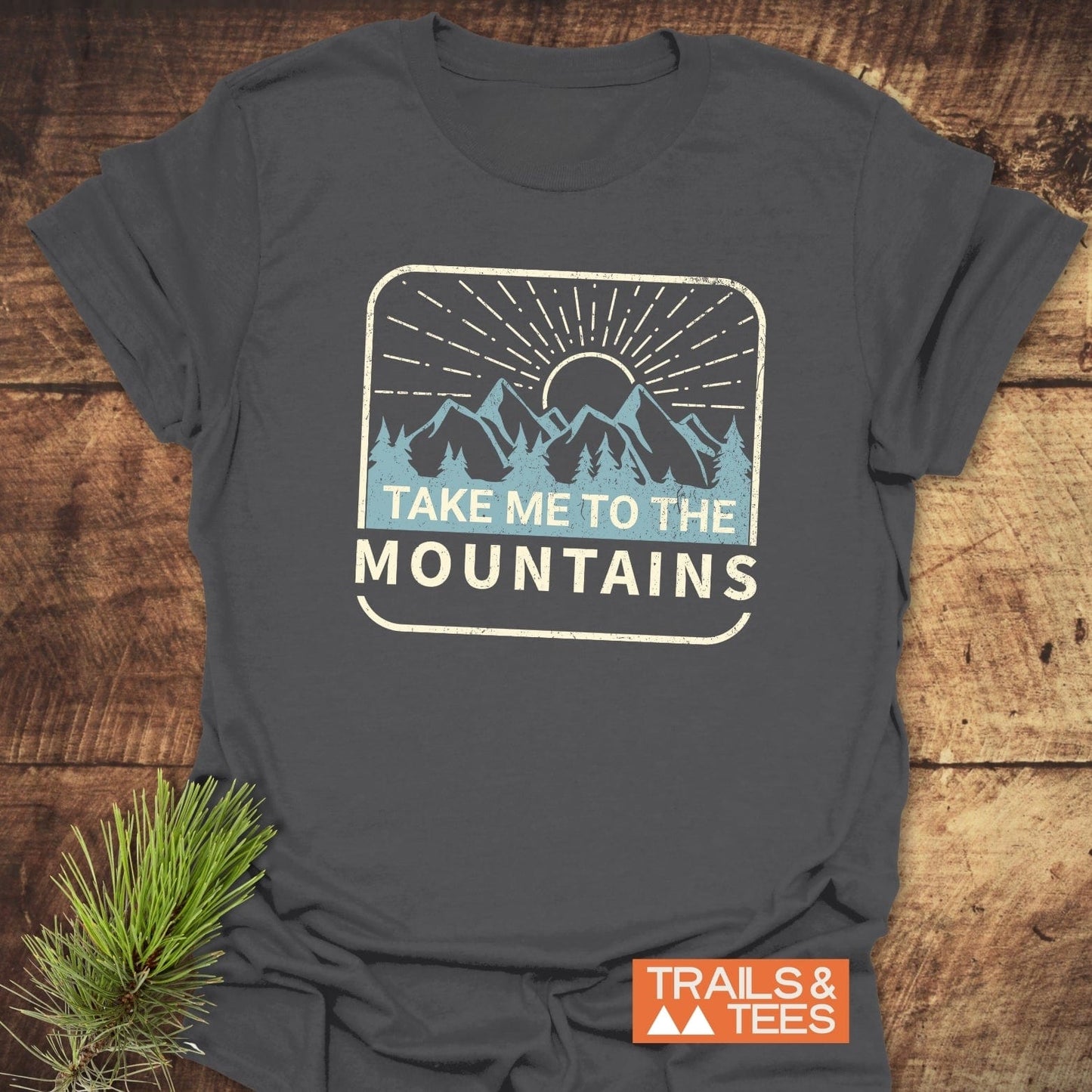 Take Me To The Mountains T-Shirt featuring a mountain graphic and slogan, made from soft ring-spun cotton, ideal for outdoor enthusiasts.