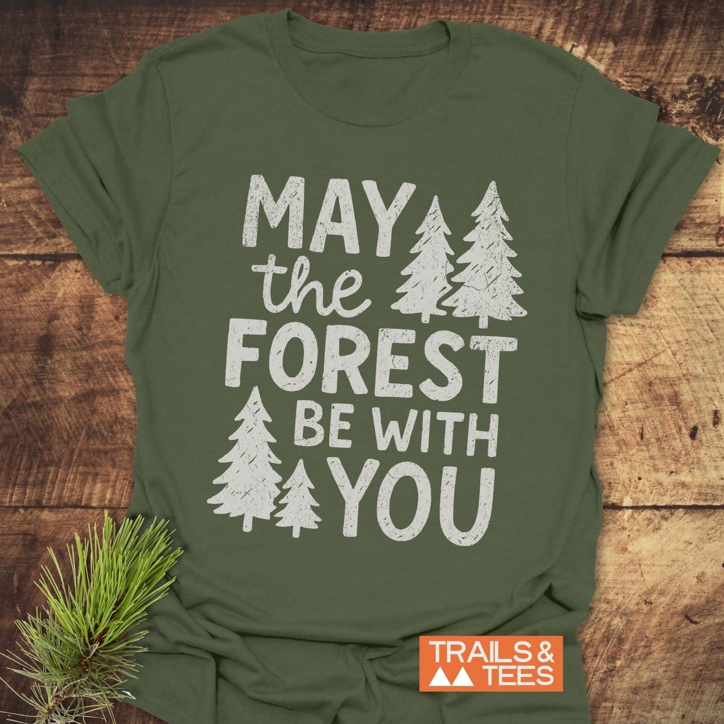 May The Forest Be With You T-Shirt: forest-green tee with pine-tree slogan, showcasing durable print and soft cotton, ideal for outdoor enthusiasts.