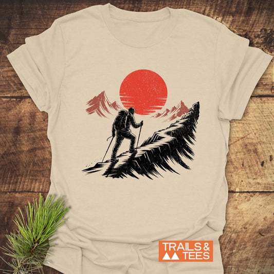 Hiker Sunset T-Shirt featuring a hiker graphic on a beige tee, crafted from soft cotton for outdoor enthusiasts, complete with Trails & Tees logo.