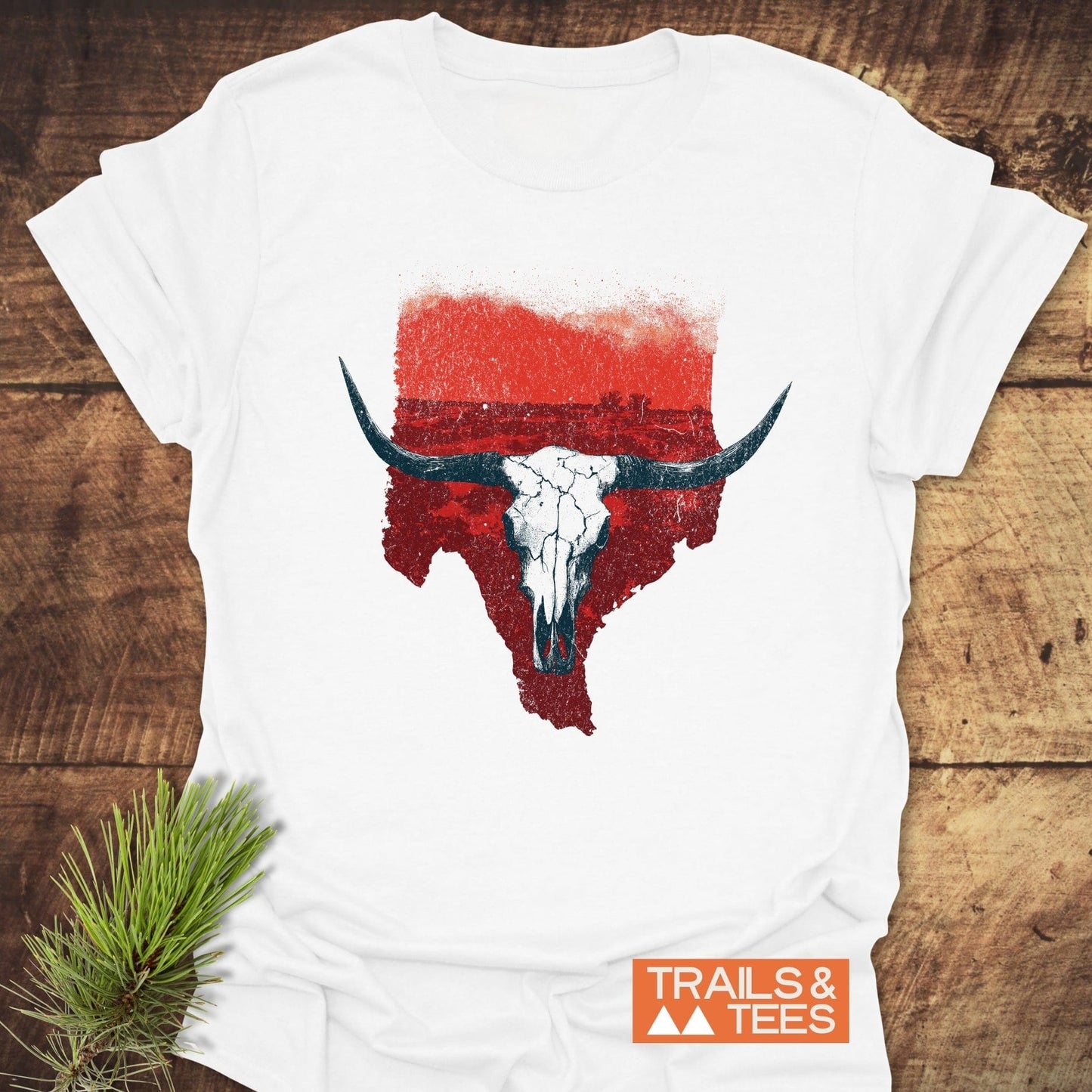 Hike Texas T-Shirt featuring a distressed Texas outline with a longhorn skull graphic, laid on wood. Crafted for comfort and durability, perfect for outdoor enthusiasts.
