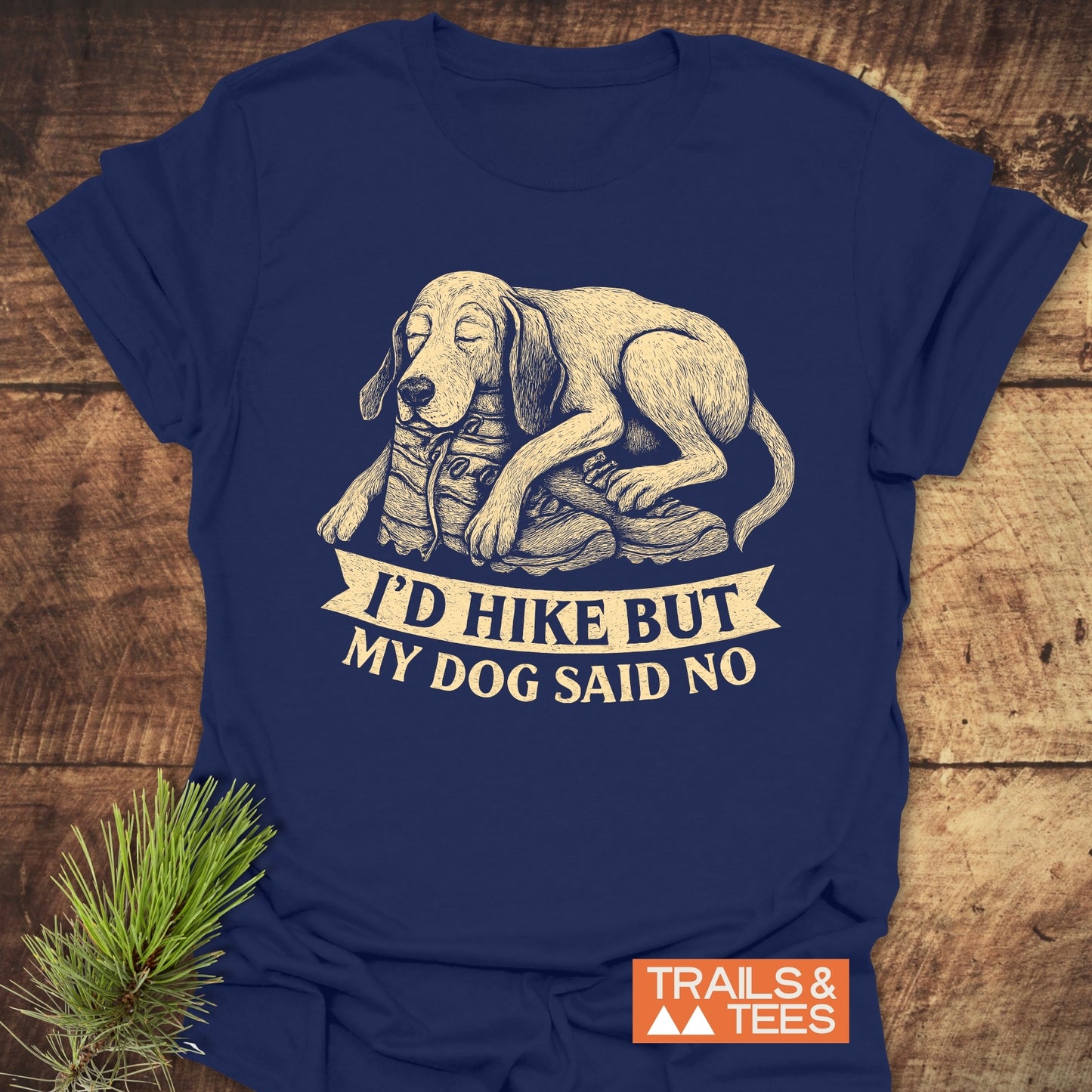 Navy-blue Dog Said No T-Shirt with a sleepy dog illustration, slogan about hiking, and a small TRAILS & TEES logo, laid on a wooden surface.