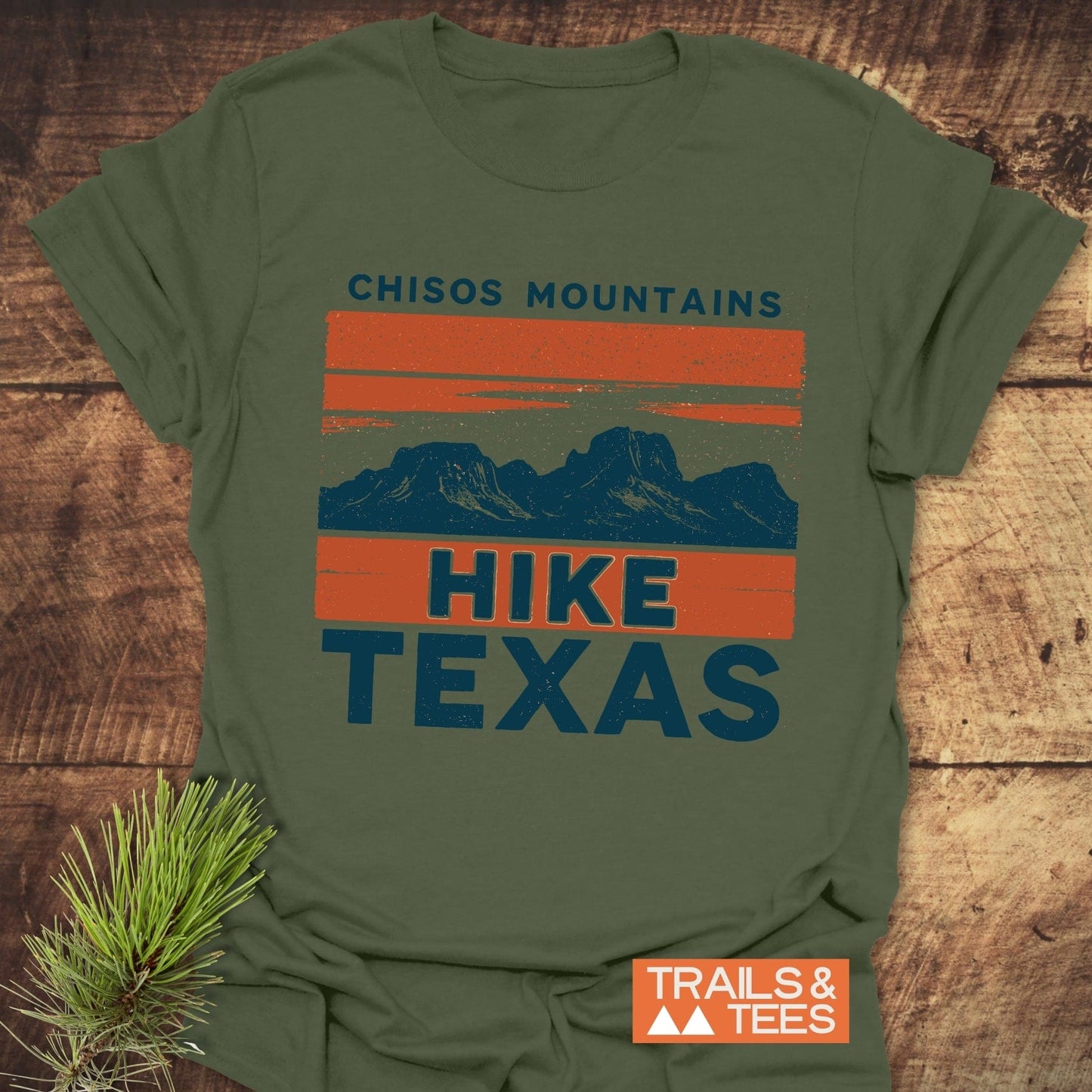 Chisos Mountains Texas T-Shirt featuring a dark blue mountain graphic on orange stripes, crafted from soft cotton, designed for comfort and durability with a Trails & Tees logo.