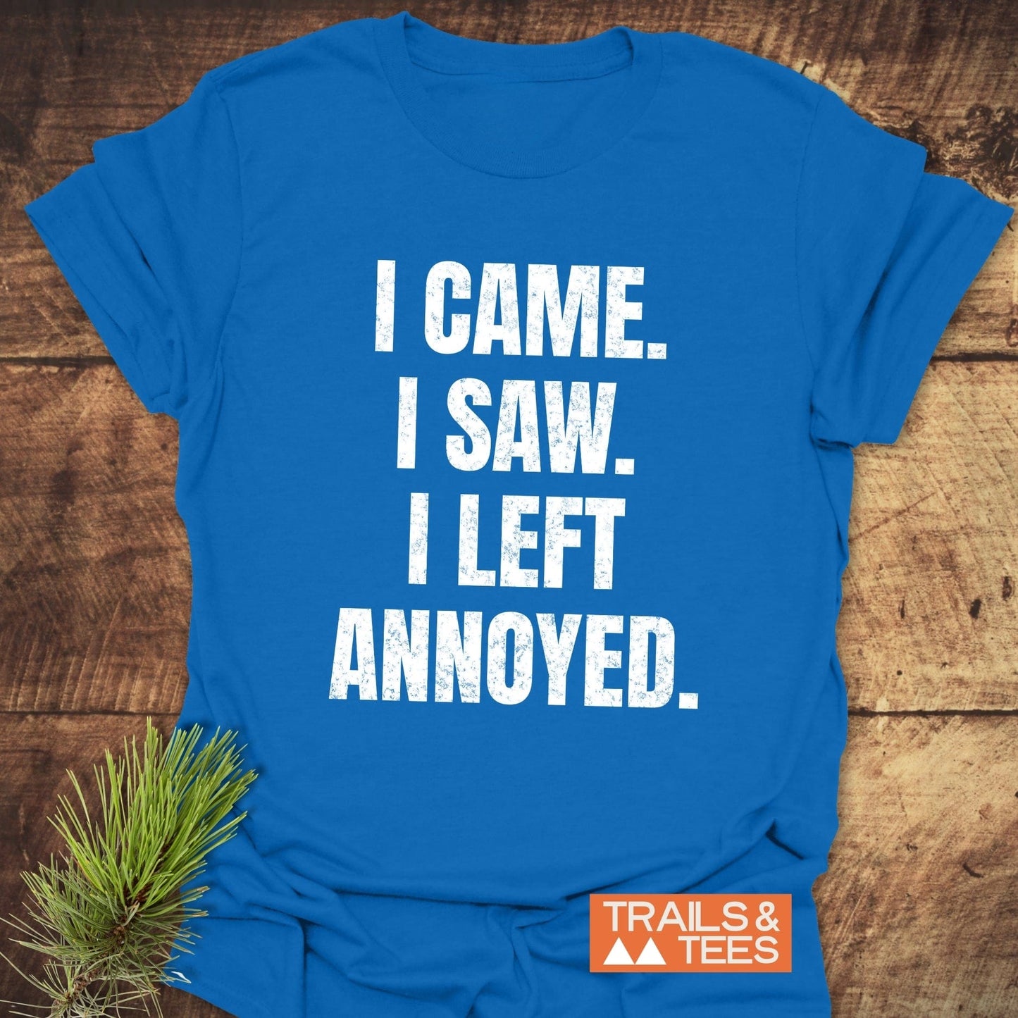 I Came. I Saw. Annoyed. T-Shirt on wood, featuring large white lettering, small orange TRAILS & TEES logo, and a pine branch accent.