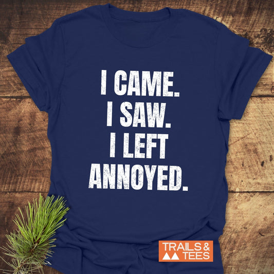 Navy-blue I Came. I Saw. Annoyed. T-shirt on wood surface with Trails & Tees logo; evergreen sprig accent.