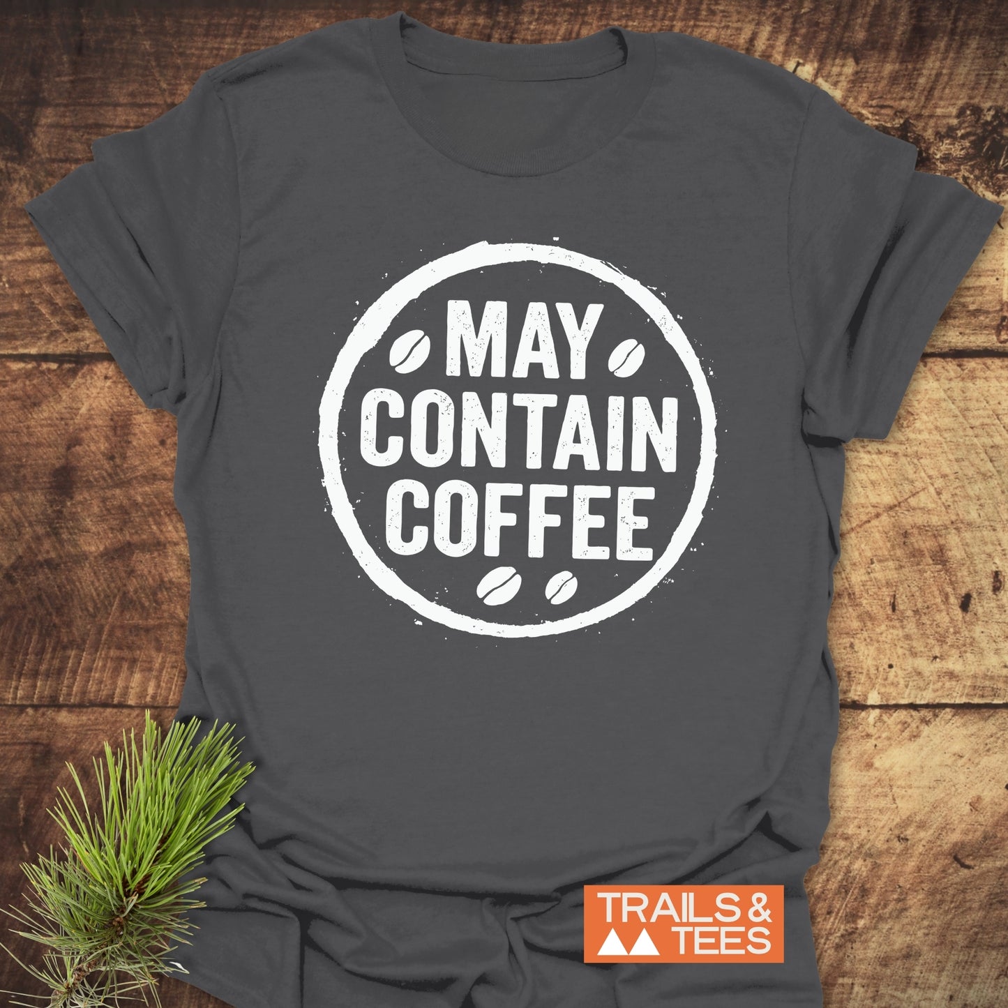 May Contain Coffee T-Shirt with white circular graphic and coffee-bean icons, laid flat. Features soft, pre-shrunk cotton for comfort; durable print and taped shoulders.