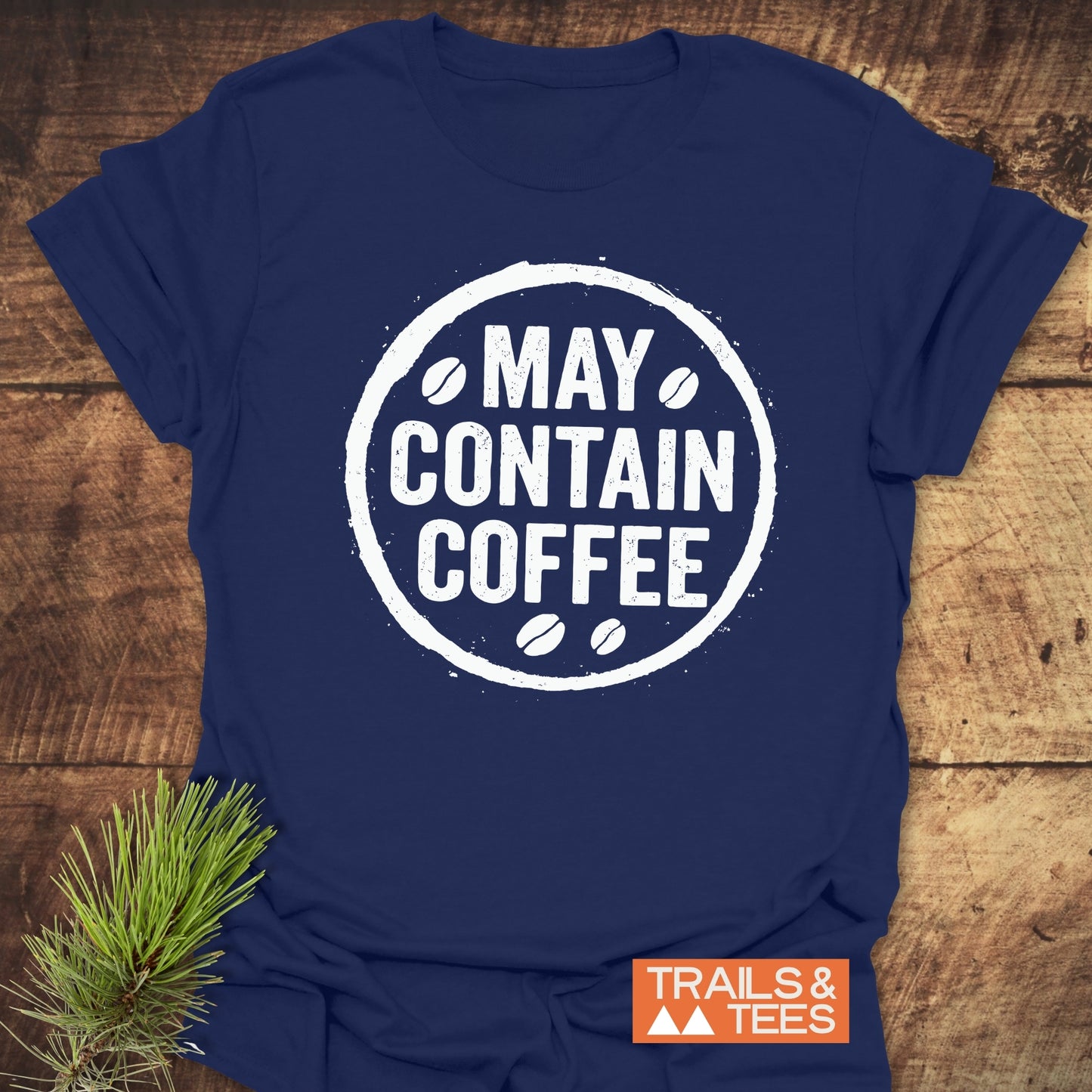 May Contain Coffee T-Shirt with distressed graphic on navy fabric, showcasing outdoor-inspired comfort and durability, featuring Trails & Tees logo and pine sprig accent.
