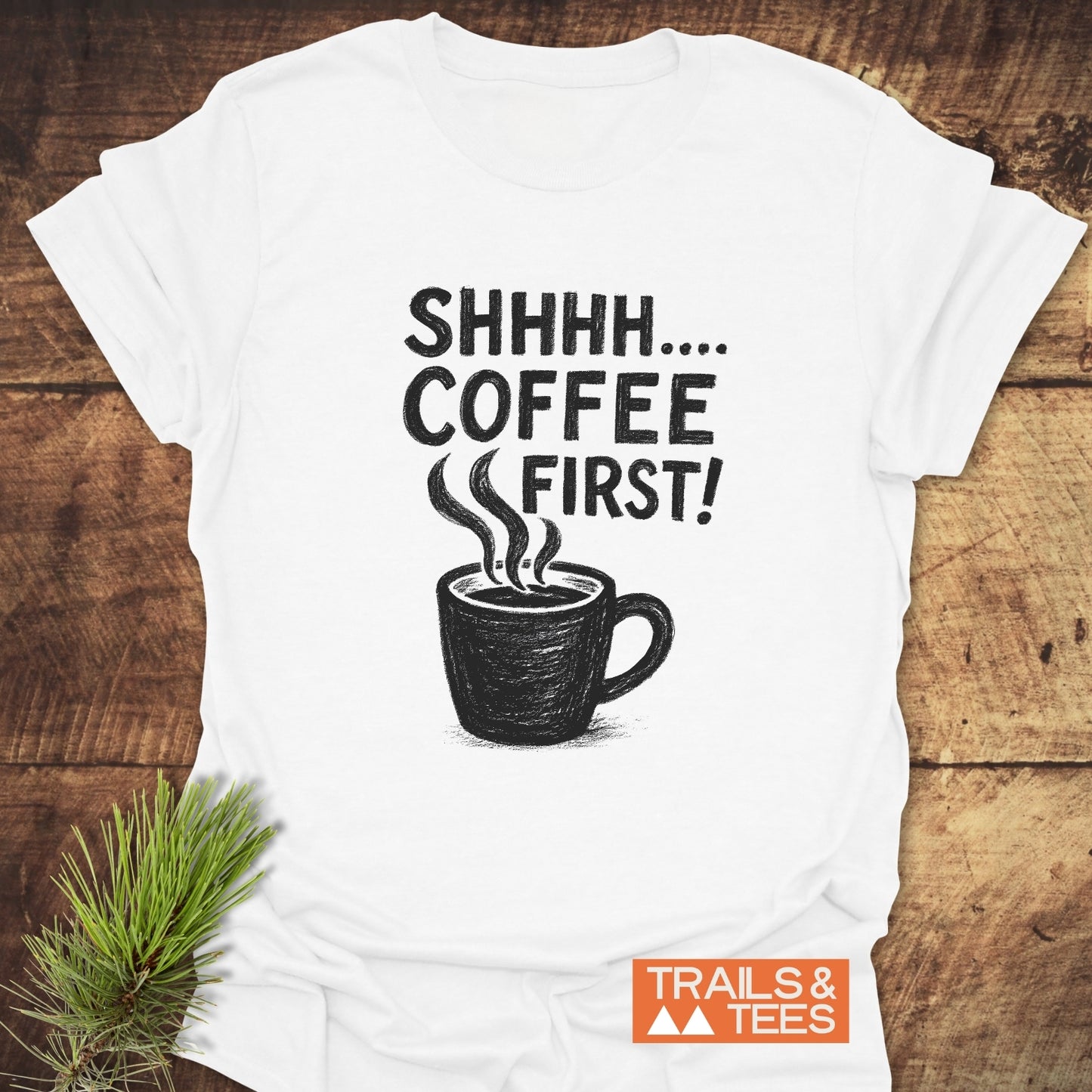 Shhhhh, Coffee First T-Shirt with a coffee mug sketch and text, laid on wood. Soft, durable ring-spun cotton, perfect for outdoor enthusiasts.