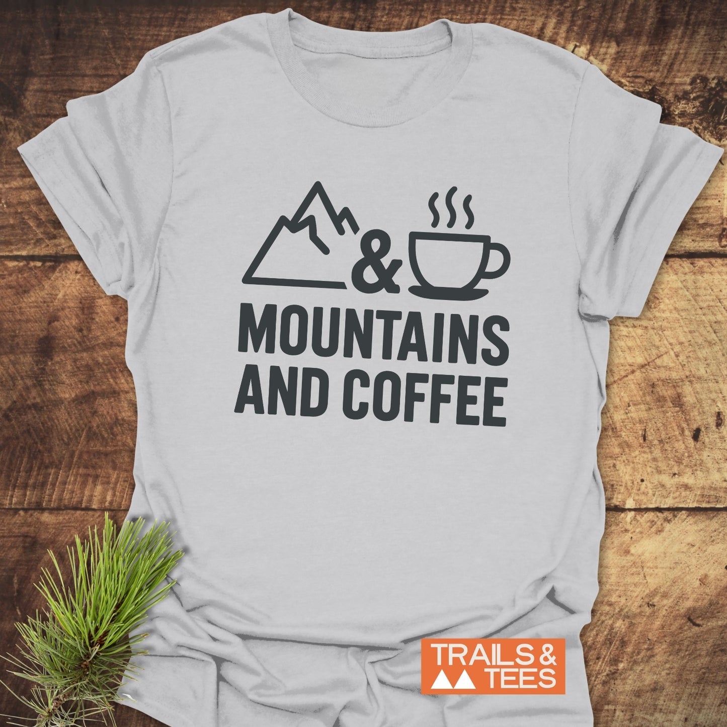 Mountains And Coffee T-Shirt featuring a mountain, ampersand, and coffee cup graphic, highlighting outdoor adventure. Crafted for comfort with durable prints and pre-shrunk fit.