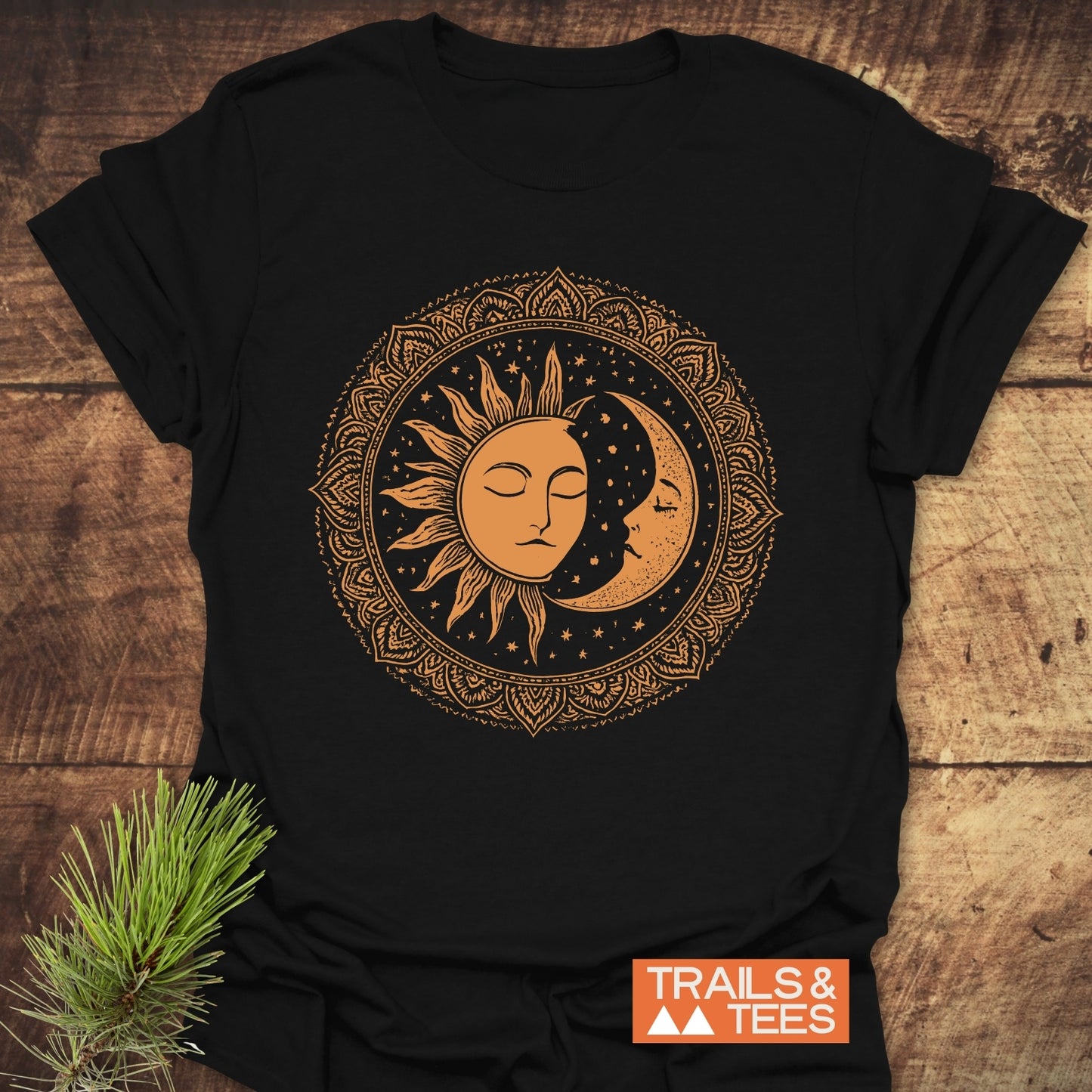 Bohemian Sun And Moon T-Shirt with a mandala sun and moon design, laid on wood. Features durable, lightweight cotton for outdoor adventures, by Trails & Tees.
