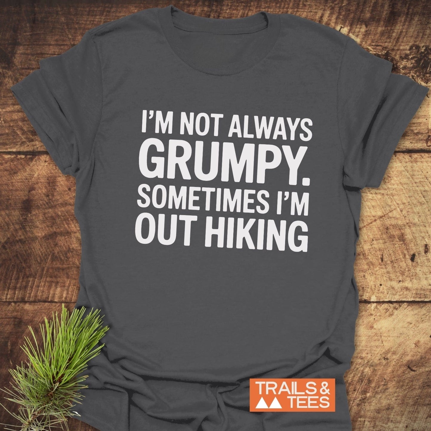 Im Not Always Grumpy T-Shirt on wooden surface, featuring bold white text and Trails & Tees logo, made of soft ring-spun cotton for outdoor enthusiasts.