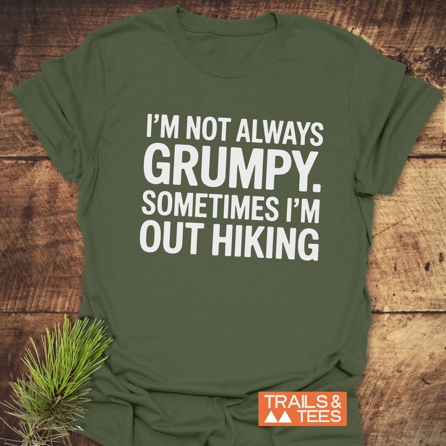 Olive-green I'm Not Always Grumpy T-shirt on wood, featuring TRAILS & TEES logo, pine sprig; crafted for comfort with durable, pre-shrunk, lightweight cotton.