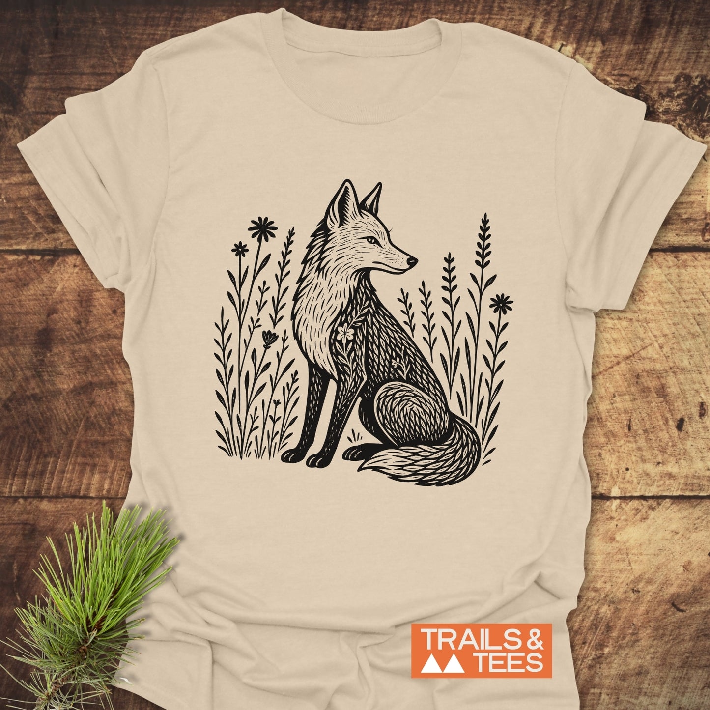 Wildflower Fox T-Shirt with a fox illustration amid meadow flowers. Soft, ring-spun cotton, pre-shrunk, durable print. Branded TRAILS & TEES, nature-themed aesthetic.