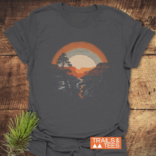 Hike Grand Canyon T-Shirt featuring a retro landscape graphic with a sun, canyon, and river. Includes TRAILS & TEES logo and pine sprig accent.