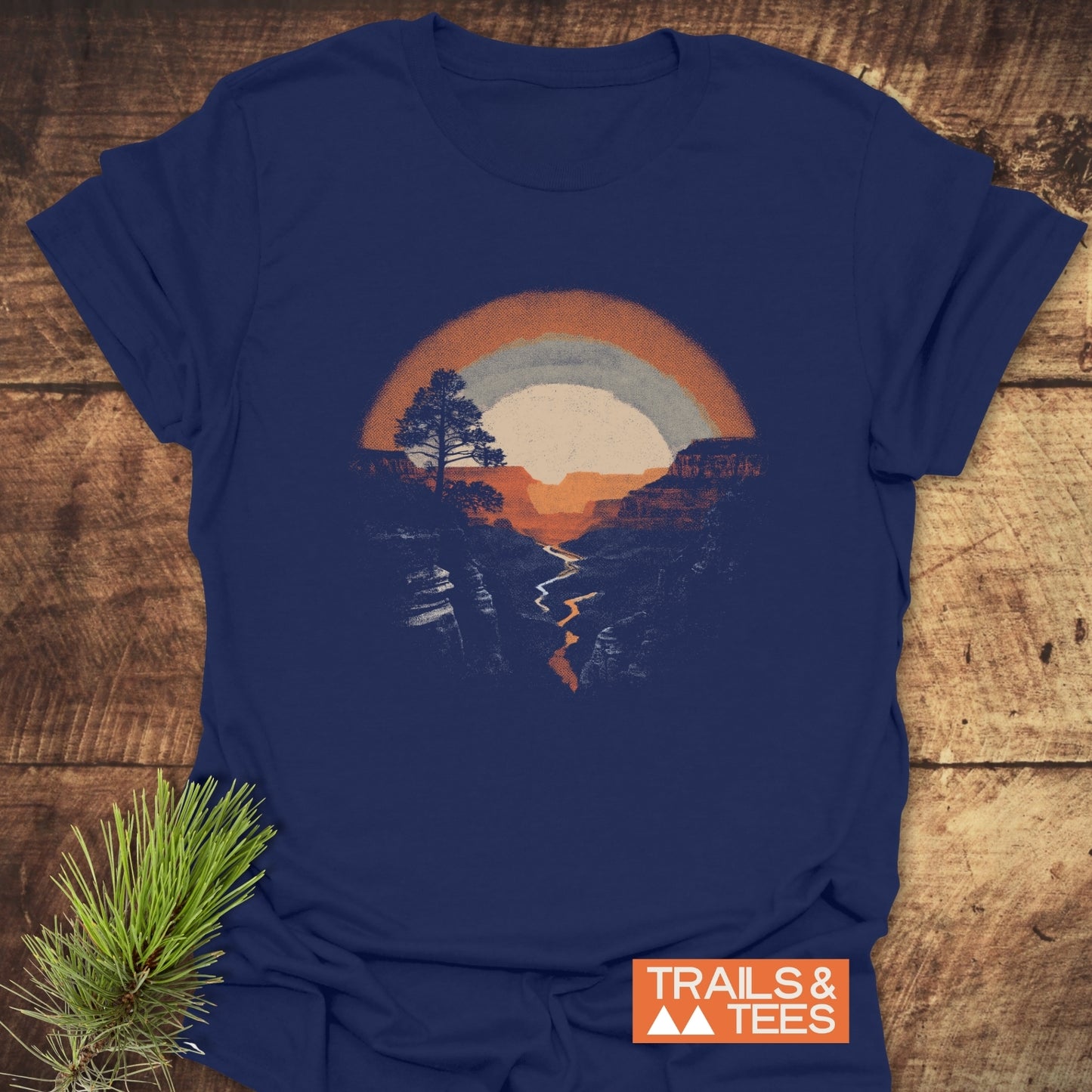 Hike Grand Canyon T-Shirt with a stylized canyon scene, featuring a sun, tree, river, and TRAILS & TEES logo, on soft, durable cotton.