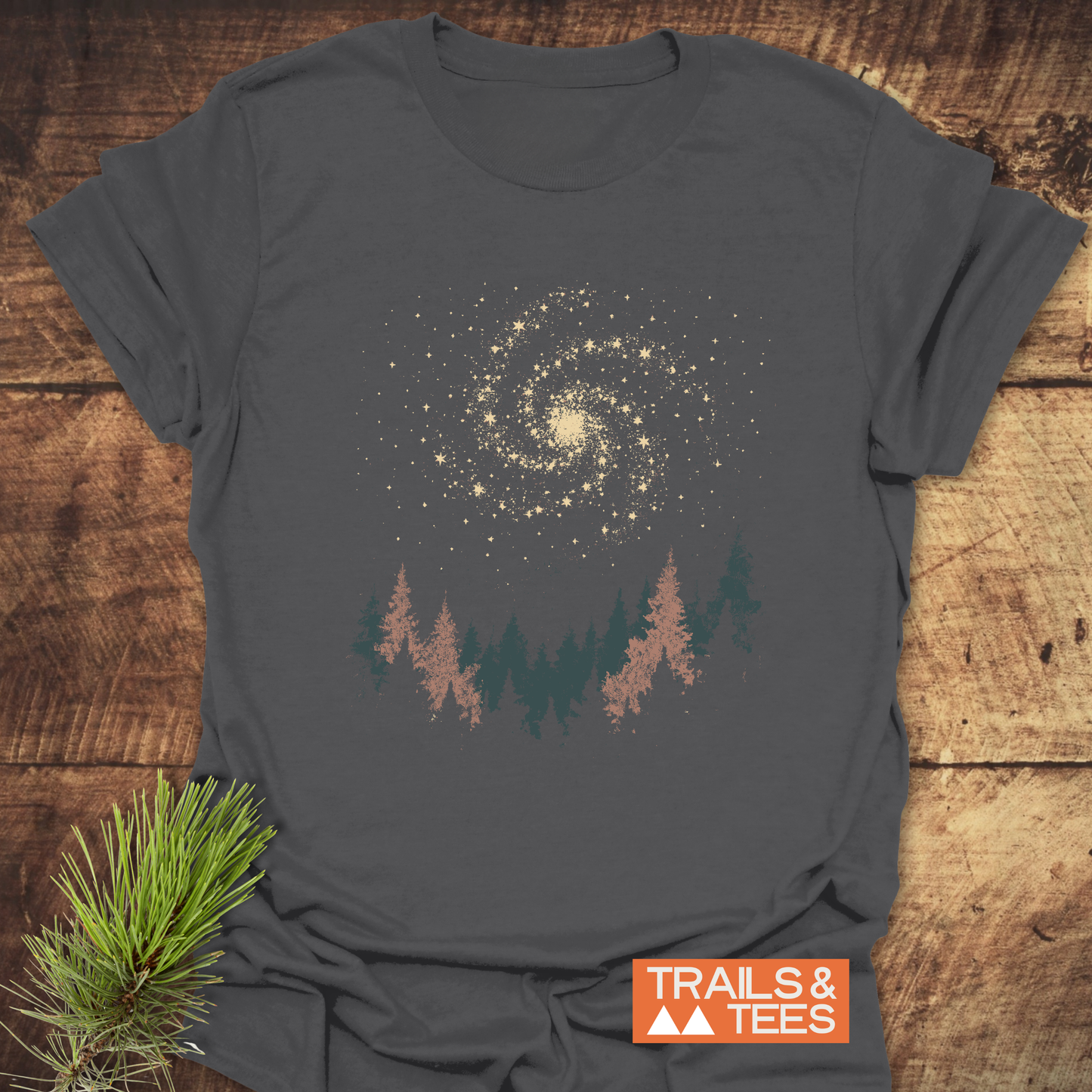 Woodland Nightsky T-Shirt featuring a galaxy and pine tree graphic, designed for outdoor enthusiasts. Made from soft cotton, showcasing durability and eco-friendly production.