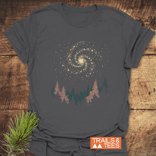 Woodland Nightsky T-Shirt featuring a galaxy and pine tree graphic, designed for outdoor enthusiasts. Made from soft cotton, showcasing durability and eco-friendly production.