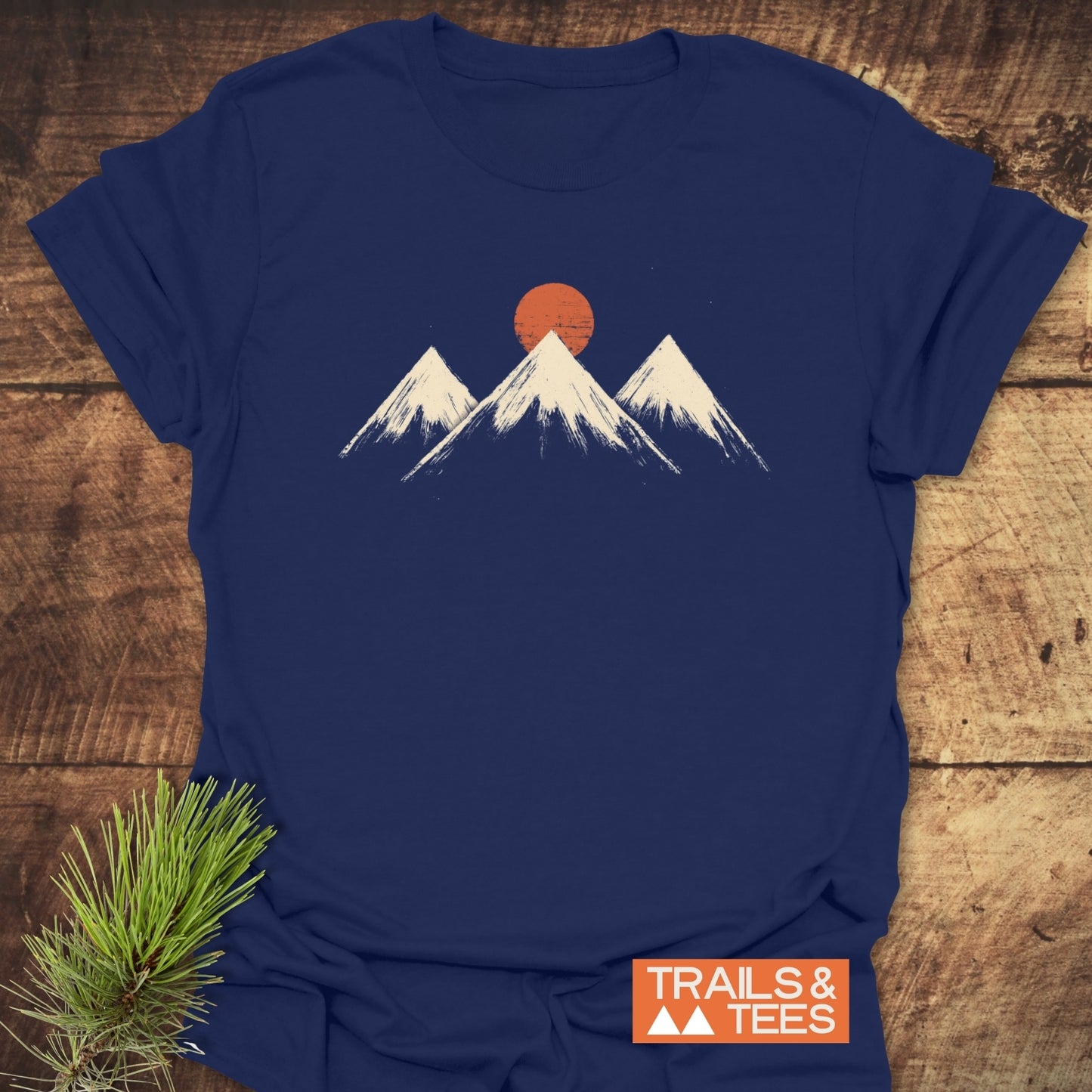 Three Mountains And Sun T-Shirt displaying snow-capped peaks and orange sun graphic, emphasizing outdoor adventure and comfort with durable, eco-friendly design.
