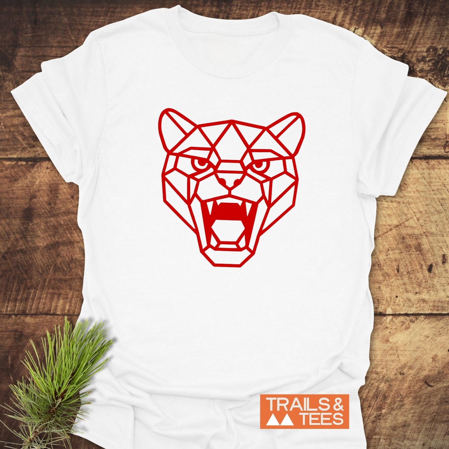 Geometric Cougar T-Shirt on rustic wood, featuring a red line-art big cat illustration. Includes TRAILS & TEES logo. Crafted for comfort and durability.