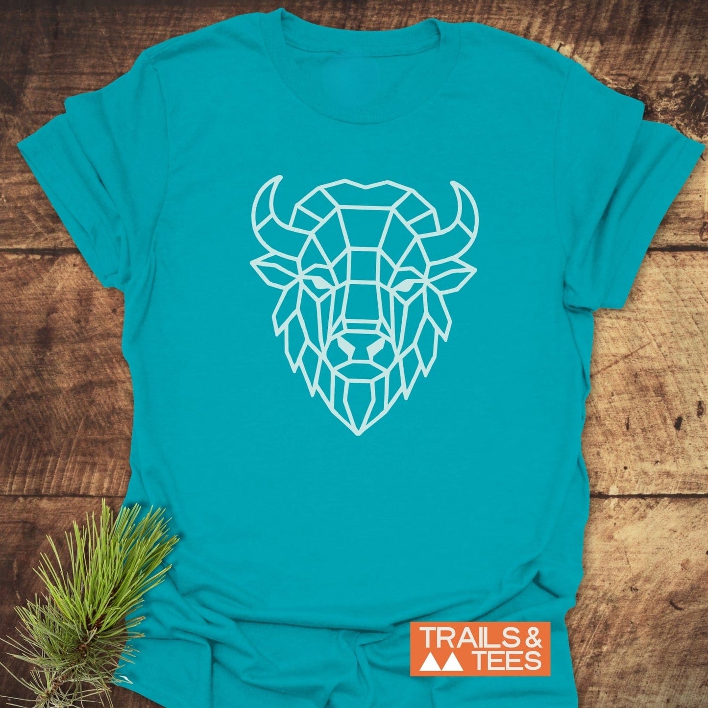 Geometric Bison T-Shirt features a white line bison design on teal cotton, offering trail-tested comfort and durability for outdoor enthusiasts.