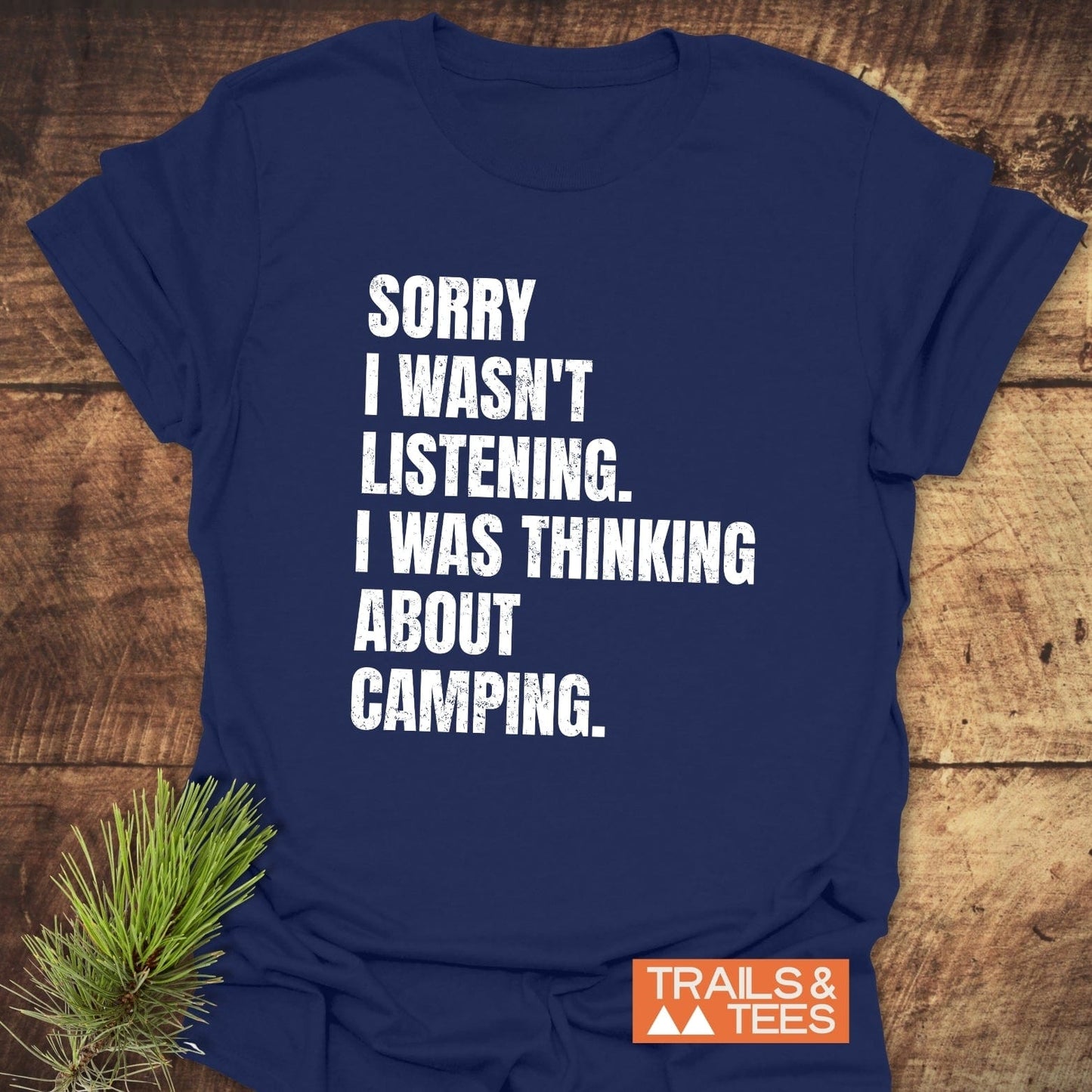 Navy blue Sorry I Wasn't Listening Camping T-Shirt with distressed white text, orange TRAILS & TEES logo, pine sprig accentuating the outdoorsy theme.