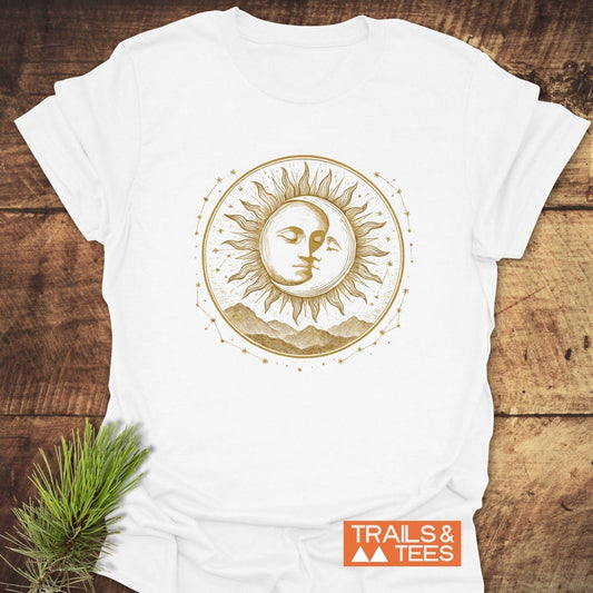 Celestial Embrace T-Shirt featuring a gold-tone sun and moon design on soft, lightweight cotton, ideal for outdoor adventures. Includes Trails & Tees logo and pine sprig.