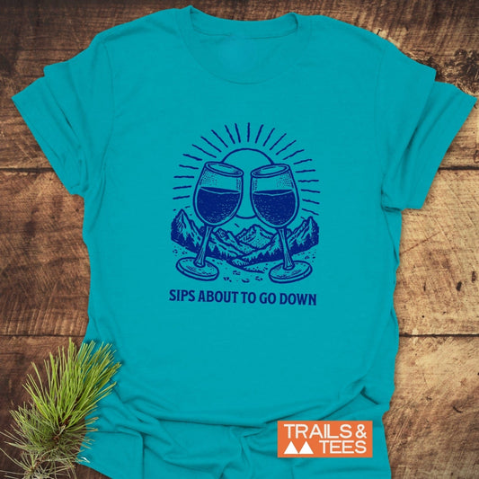 Sips About To Go Down T-Shirt featuring clinking wine glasses and mountain graphic, crafted from soft ring-spun cotton, ideal for outdoor adventures.