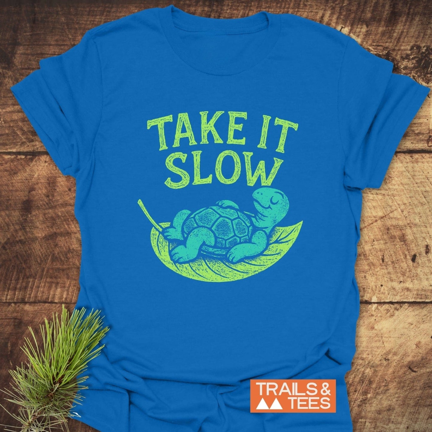 Take It Slow T-Shirt features a turtle on a leaf hammock with TAKE IT SLOW text, ensuring comfort and durability with its ring-spun cotton fabric.