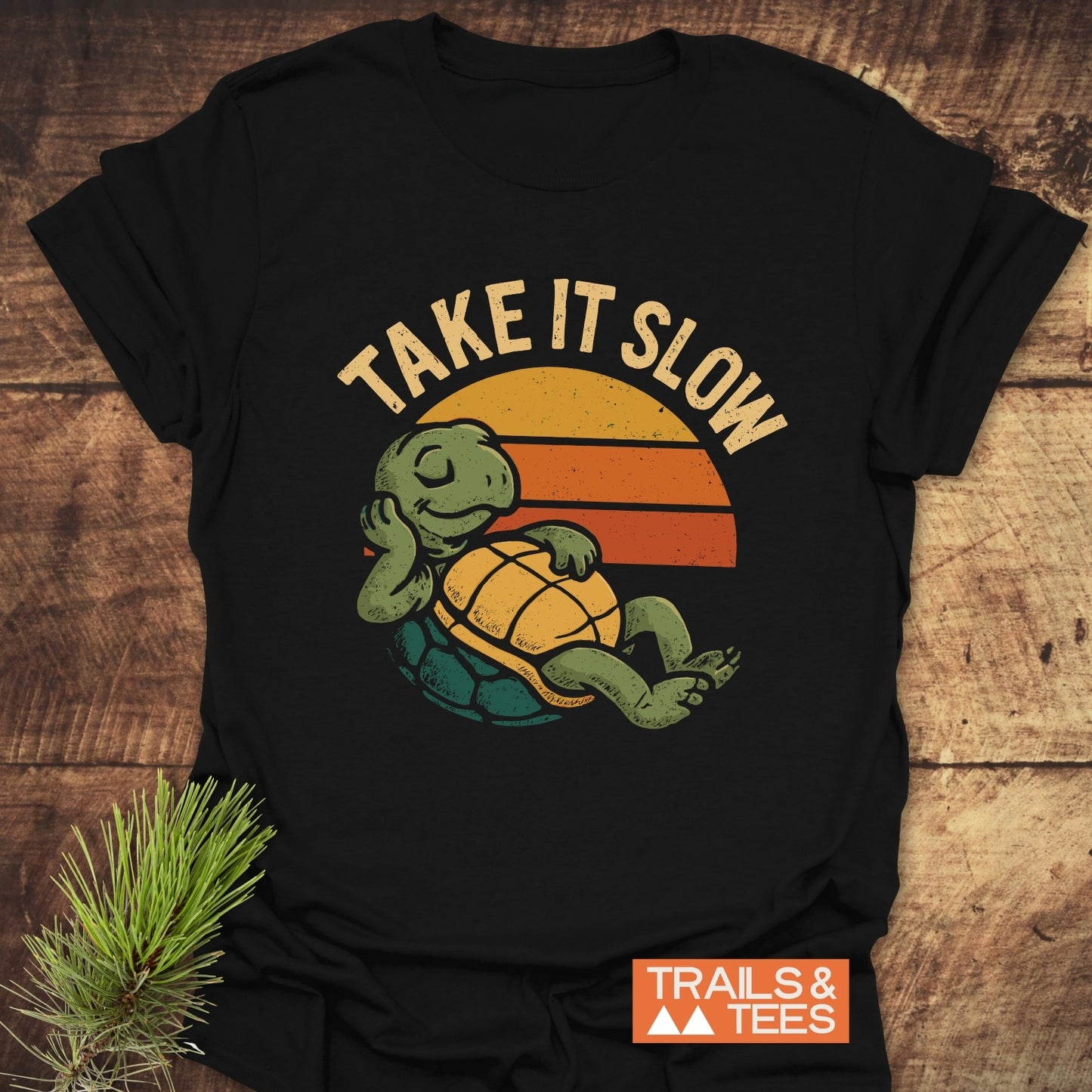 Take It Slow Turtle T-Shirt with a retro turtle graphic and TAKE IT SLOW slogan, crafted from soft cotton, featuring durable prints and a small TRAILS & TEES label.