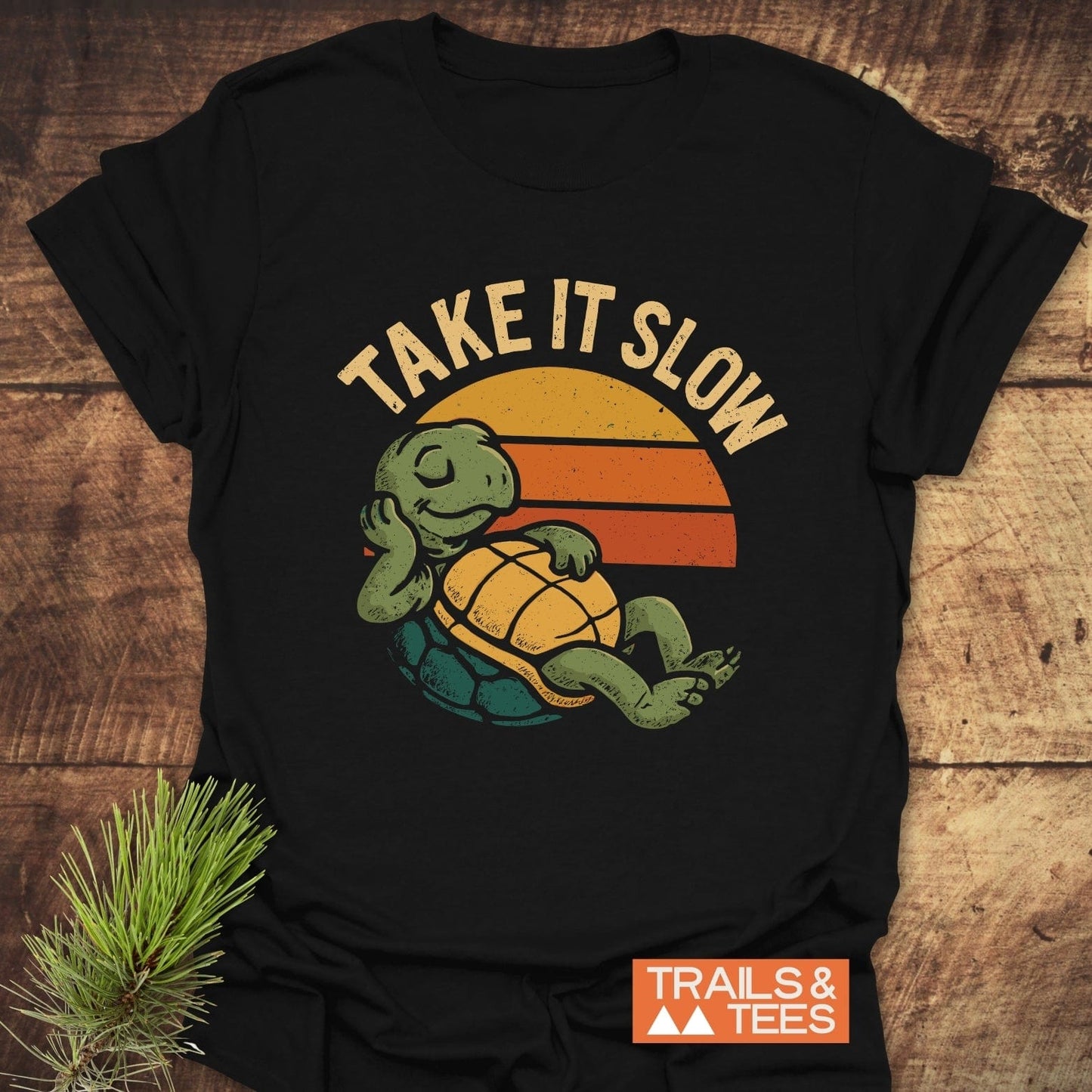 Take It Slow Turtle T-Shirt with a retro turtle graphic and TAKE IT SLOW slogan, crafted from soft cotton, featuring durable prints and a small TRAILS & TEES label.