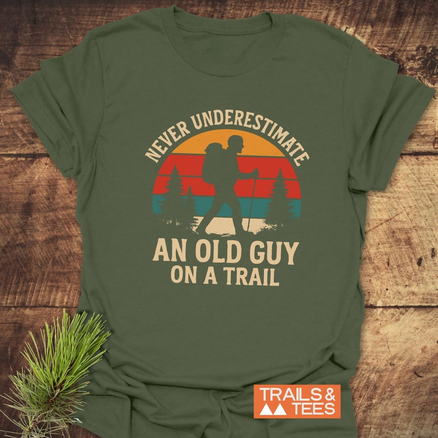 Never Underestimate T-Shirt with a vintage-style backpacker graphic, slogan, and Trails & Tees logo, crafted from soft, durable ring-spun cotton.