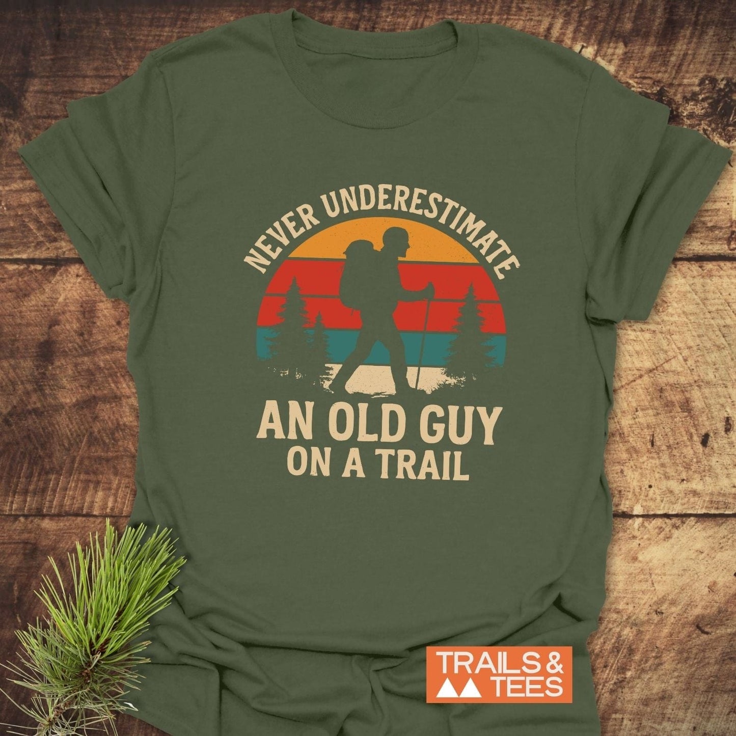 Never Underestimate T-Shirt with a vintage-style backpacker graphic, slogan, and Trails & Tees logo, crafted from soft, durable ring-spun cotton.