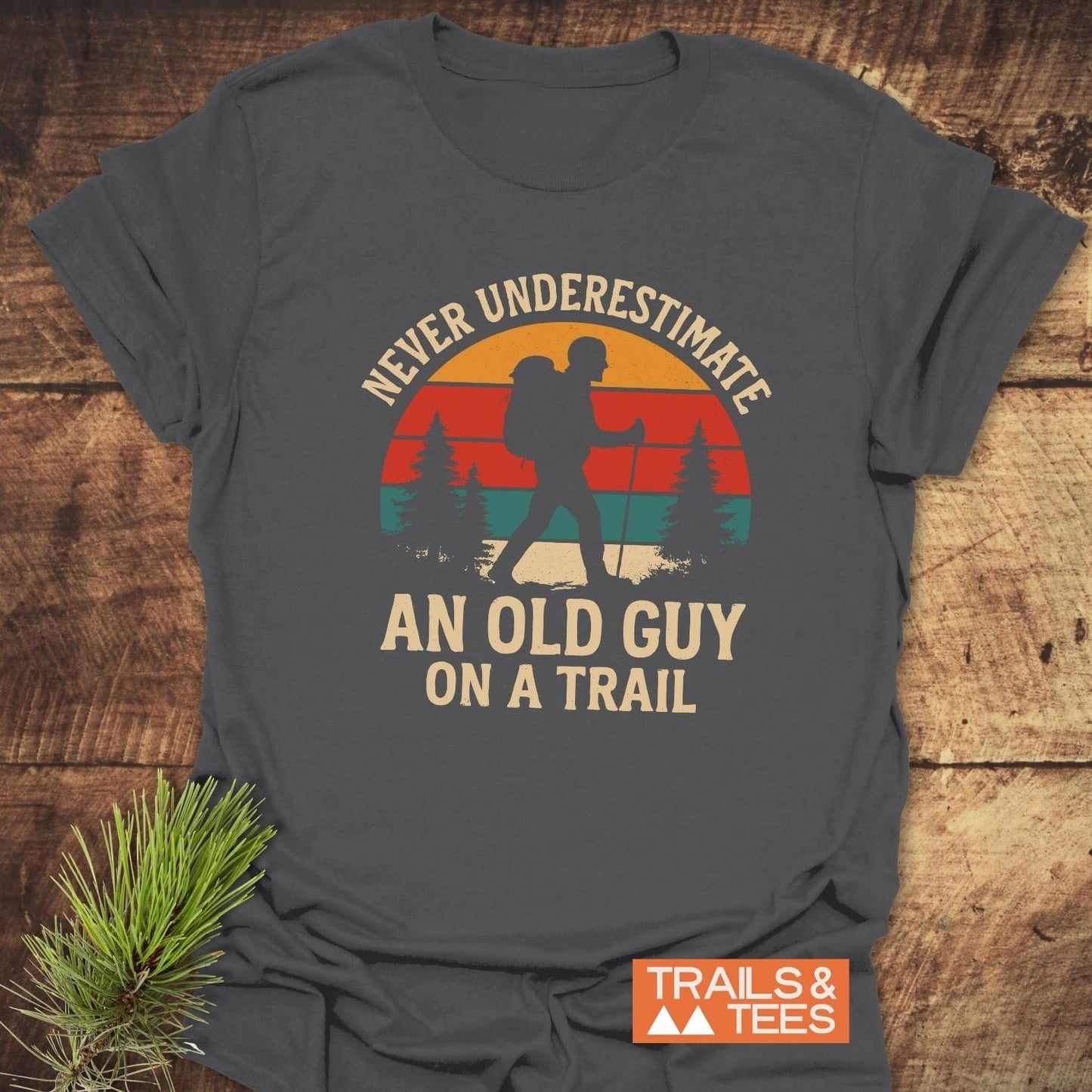 Never Underestimate T-Shirt featuring a vintage hiker graphic and slogan, crafted from soft ring-spun cotton with durable prints, ideal for outdoor enthusiasts.