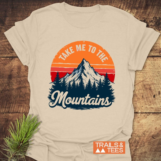Take Me To The Mountains T-Shirt featuring a mountain and sunset graphic on soft cotton, designed for comfort and outdoor enthusiasts.