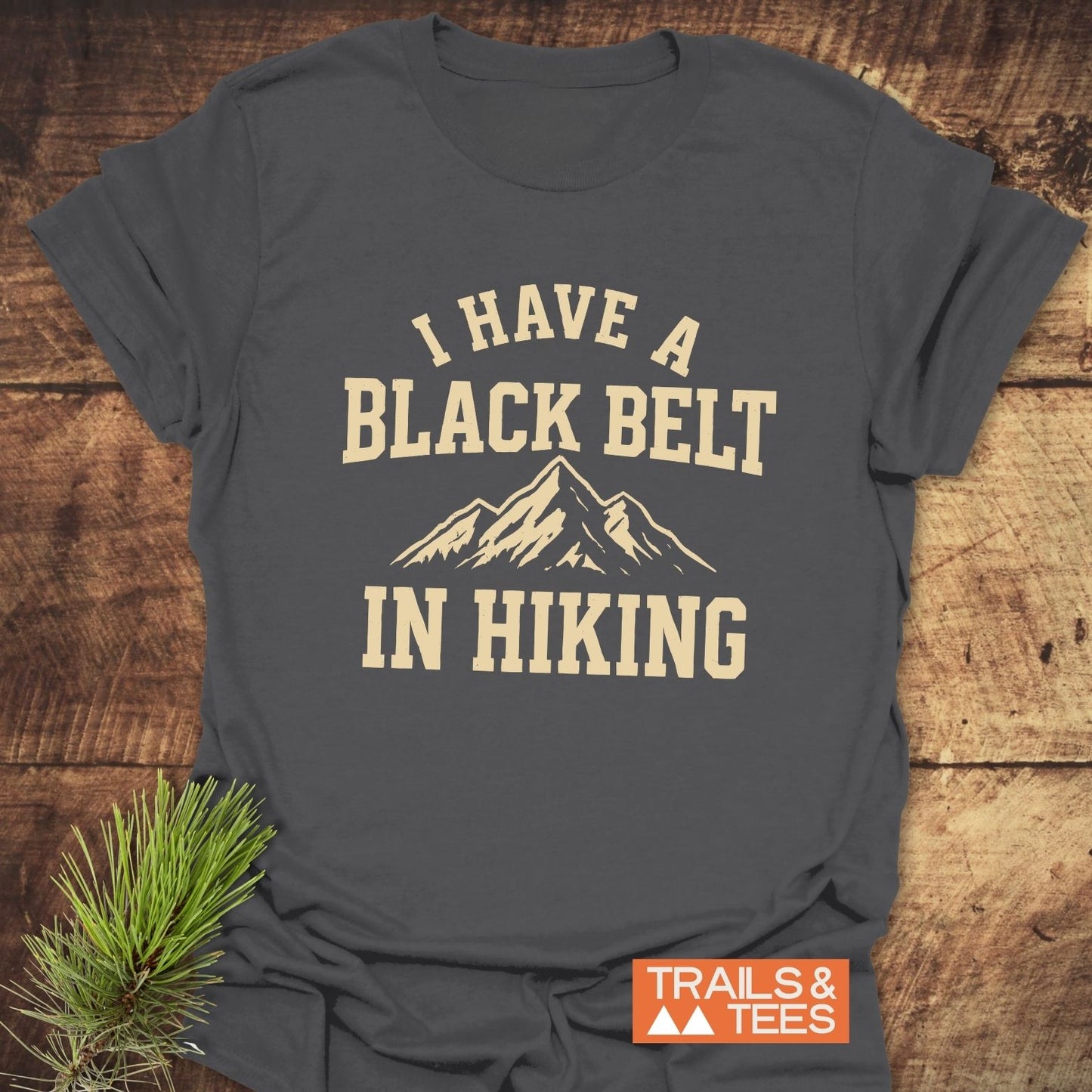 Black Belt In Hiking T-Shirt with mountain graphic and slogan. Soft ring-spun cotton, pre-shrunk, durable print. Designed for outdoor enthusiasts.