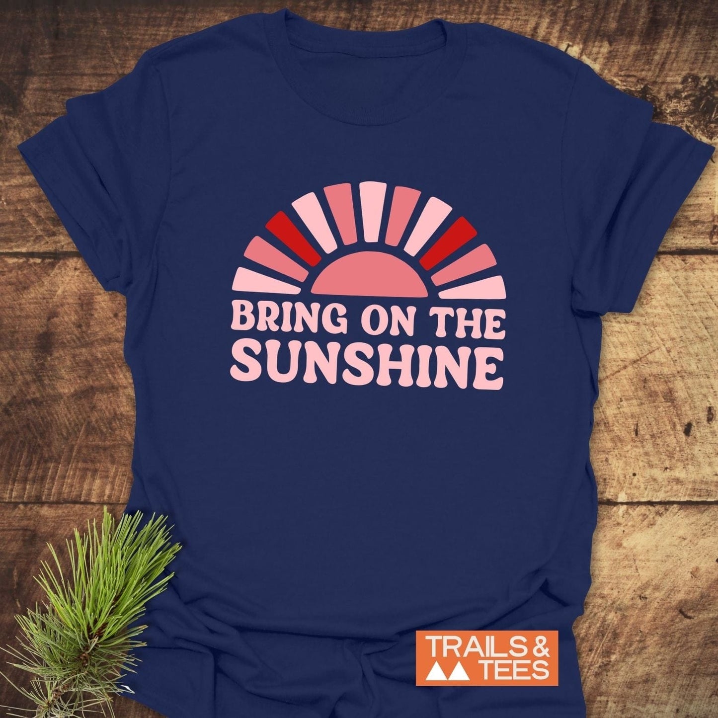 Bring On The Sunshine T-Shirt featuring a half-sun graphic and slogan, crafted from soft ring-spun cotton with durable prints, styled with a pine sprig.