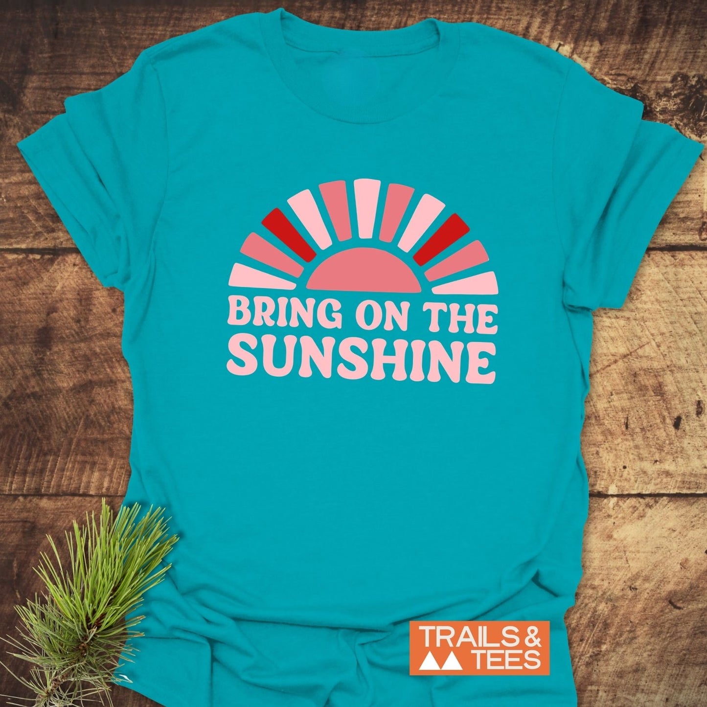Bring On The Sunshine T-Shirt featuring a half-sun design with pink rays, slogan, and Trail-tested comfort on lightweight, ring-spun cotton for outdoor adventures.